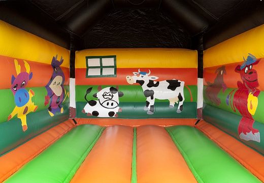 Commandez un château gonflable standard pour enfants dans des couleurs vives avec un grand objet 3D d'une vache sur le dessus. Châteaus gonflablex à vendre en ligne chez JB Gonflables France