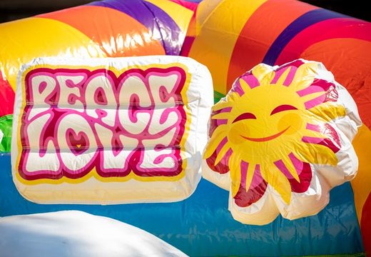 Commandez un château gonflable multijoueur super gonflable dans le thème hippie avec de nombreuses couleurs pour les enfants